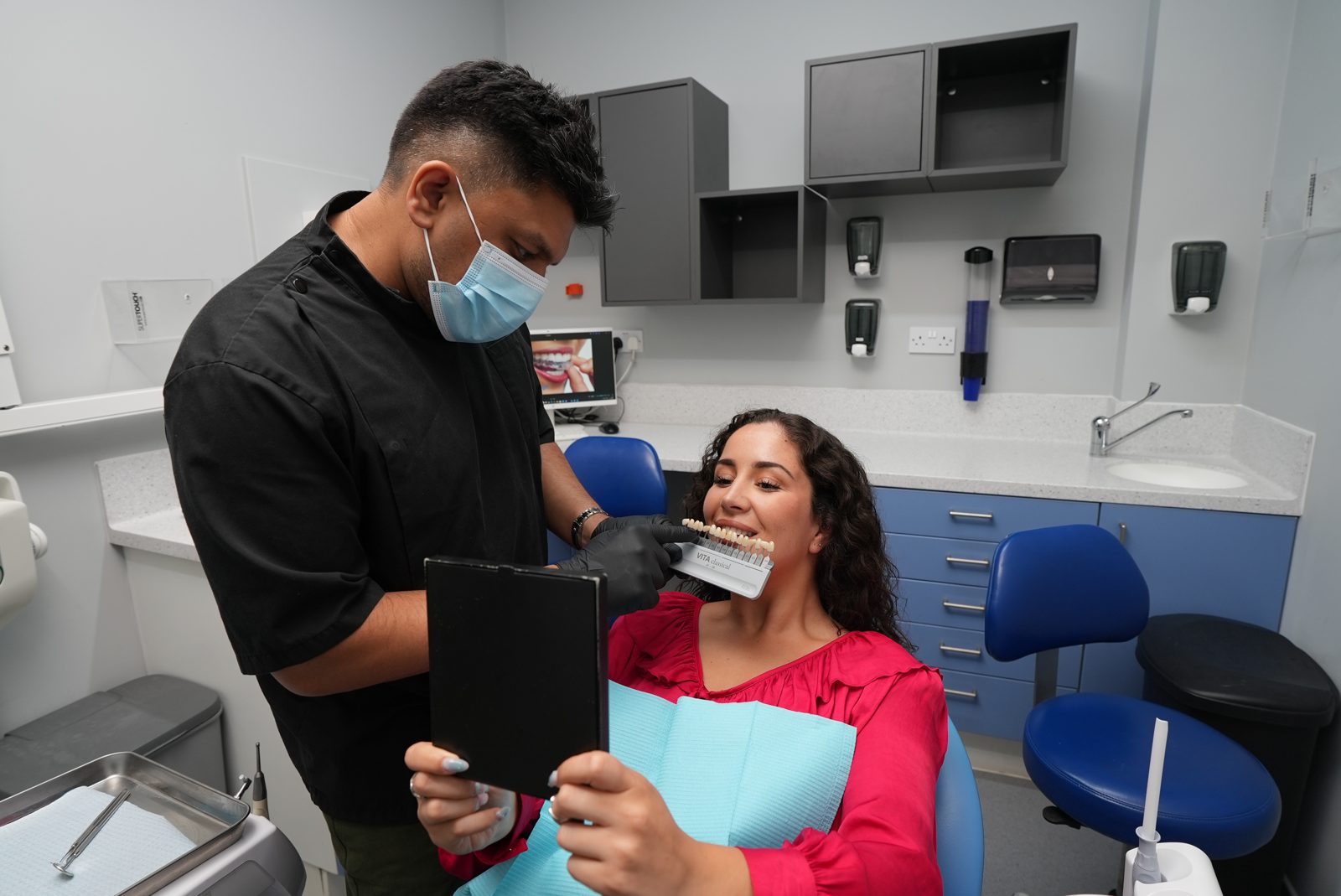 Dentist checking tooth shade and examining a patient at Welling Dental Studio